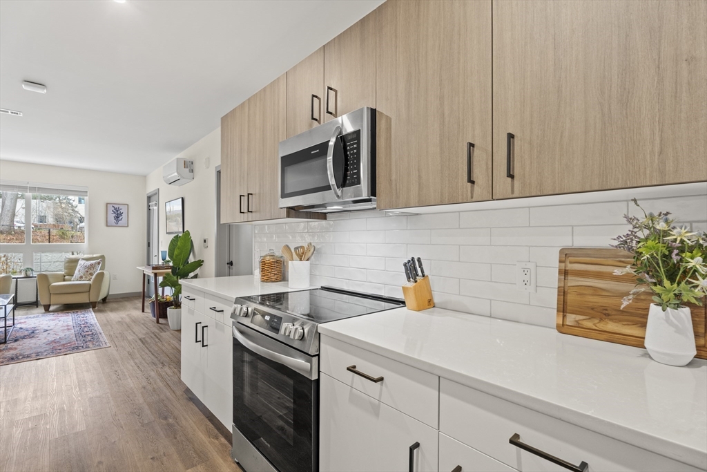 203 Lowell Street, Unit 103 Wilmington, MA 01887 - Photo 3 of 39 a kitchen with stainless steel appliances white cabinets and wooden floor