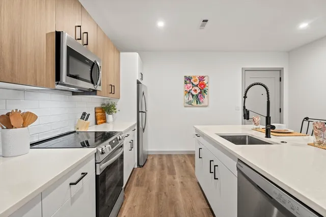 a kitchen with stainless steel appliances granite countertop a sink and a stove top oven with wooden floor