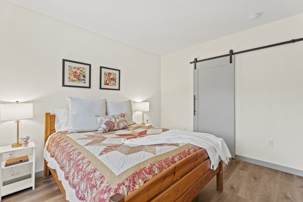 203 Lowell Street, Unit 103 Wilmington, MA 01887 - Photo 9 of 39 a bedroom with a bed and a painting on the wall