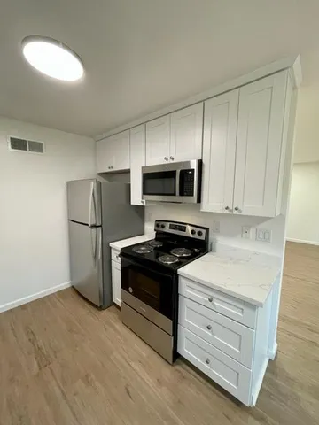 a kitchen with white cabinets and stainless steel appliances