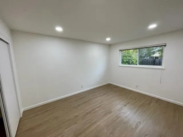 an empty room with wooden floor and windows