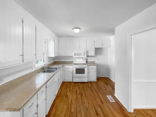 a kitchen with wooden floors a sink stainless steel appliances and cabinets