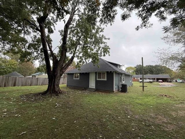 a view of backyard with large trees and wooden fence