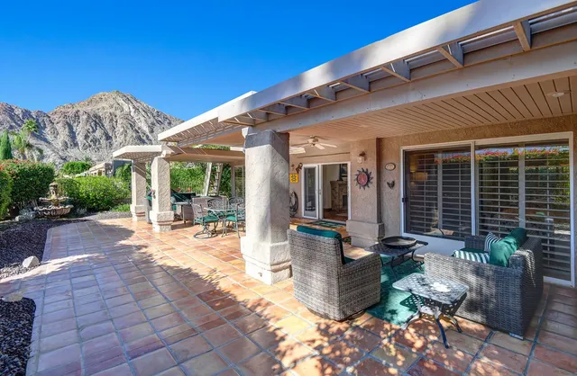 a view of a patio with table and chairs potted plants and floor to ceiling window and potted plants