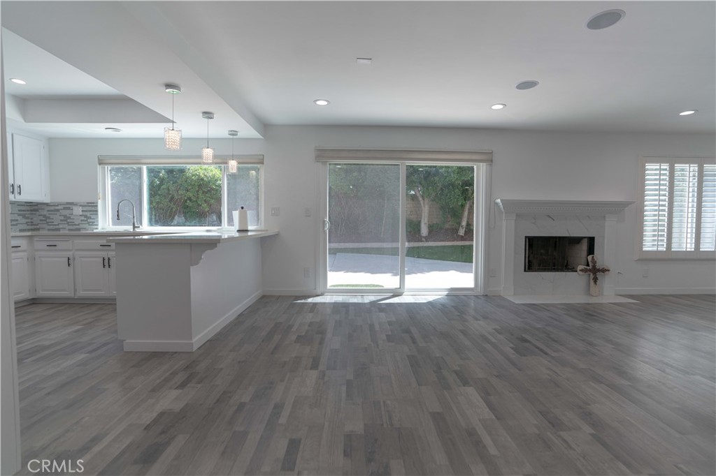 12230 Stewarton Drive Porter Ranch, CA 91326 - Photo 14 of 37 an empty room with wooden floor fireplace and windows