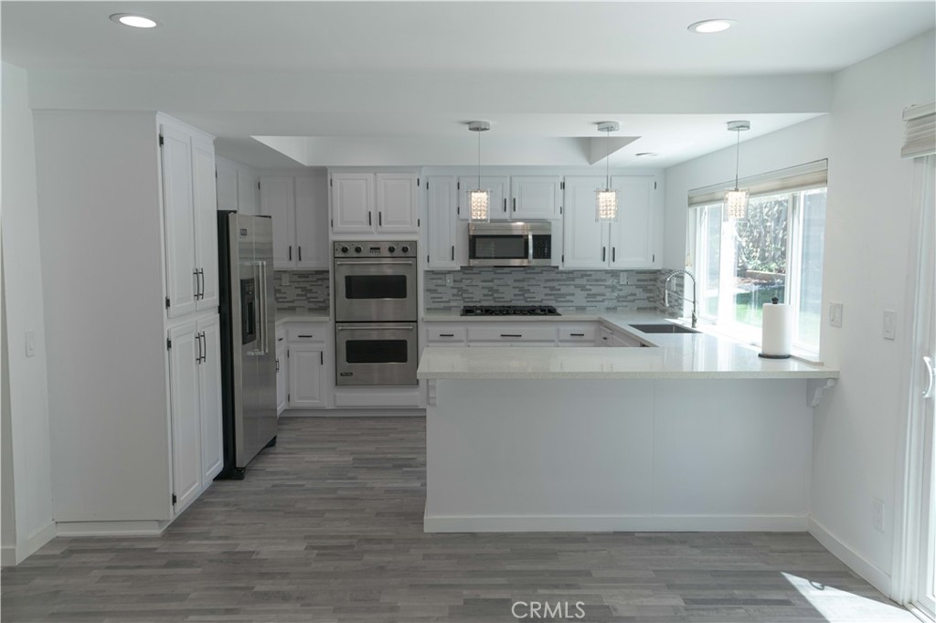 12230 Stewarton Drive Porter Ranch, CA 91326 - Photo 19 of 37 a kitchen with stainless steel appliances a refrigerator and a stove top oven