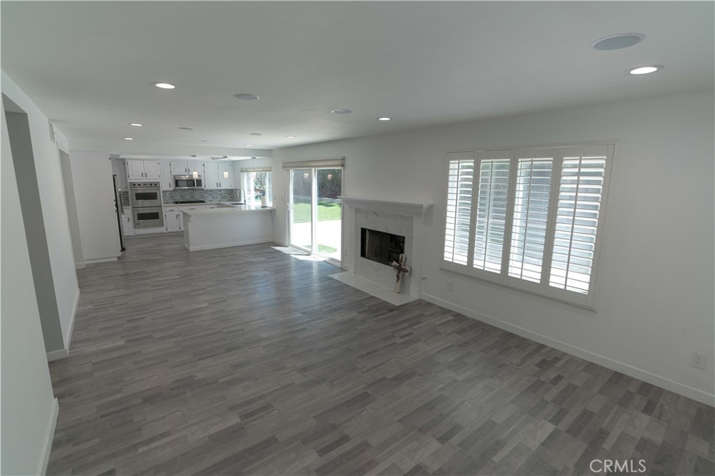 12230 Stewarton Drive Porter Ranch, CA 91326 - Photo 24 of 37 an empty room with wooden floor and a kitchen