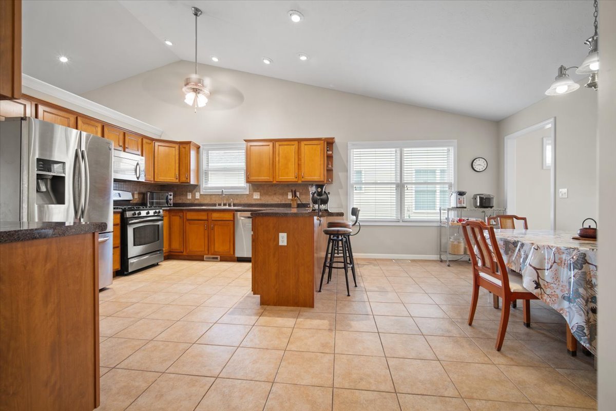 1600 Belclare Road Normal, IL 61761 - Photo 14 of 40 a kitchen with stainless steel appliances granite countertop a stove top oven a sink dishwasher a dining table and chairs with wooden floor