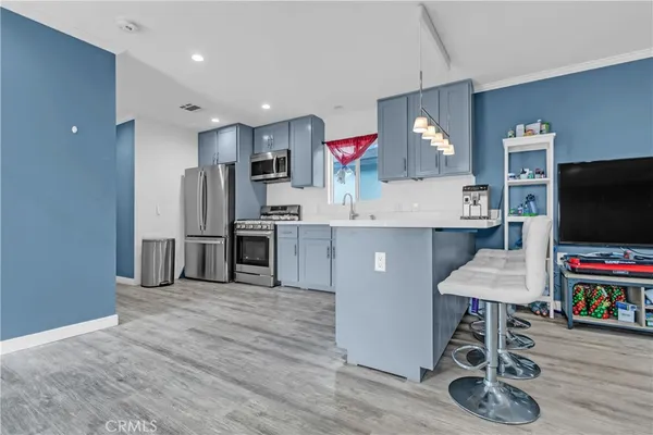 a kitchen with stainless steel appliances a refrigerator and a wooden floor