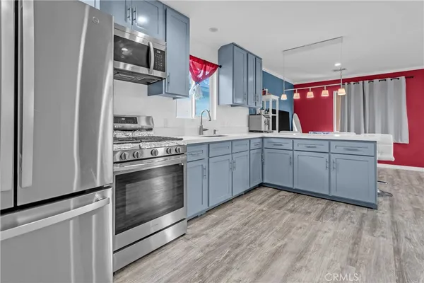 a kitchen with stainless steel appliances a sink cabinets and wooden floor