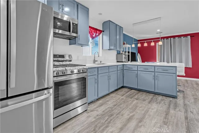 a kitchen with stainless steel appliances a sink cabinets and wooden floor
