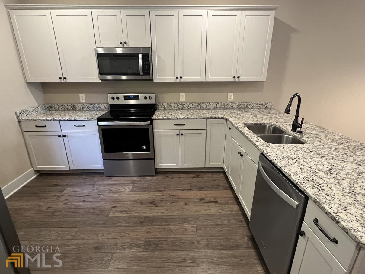 860 South Harkness Street, Unit G Jackson, GA 30233 - Photo 7 of 21 a kitchen with granite countertop a sink stove and white cabinets