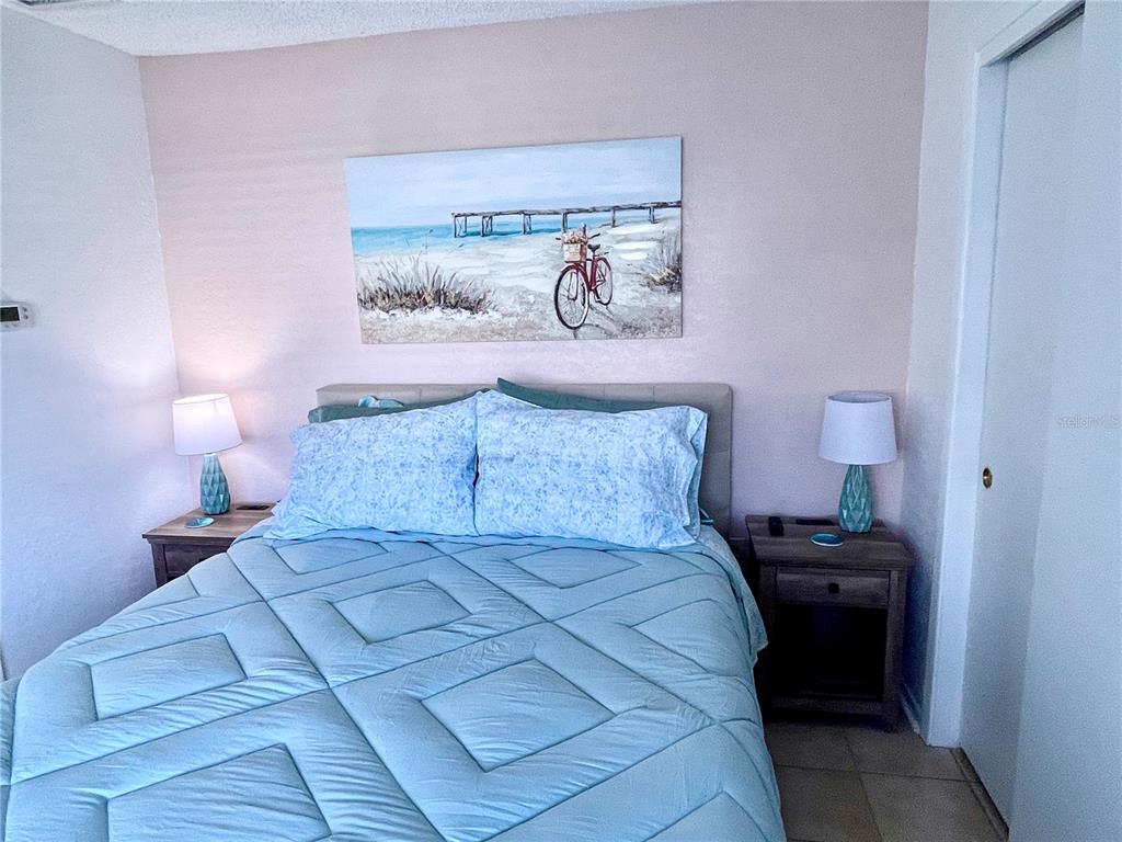 165 Medallion Boulevard, Unit H Madeira Beach, FL 33708 - Photo 13 of 20 a bedroom with a bed and a lamp on dresser