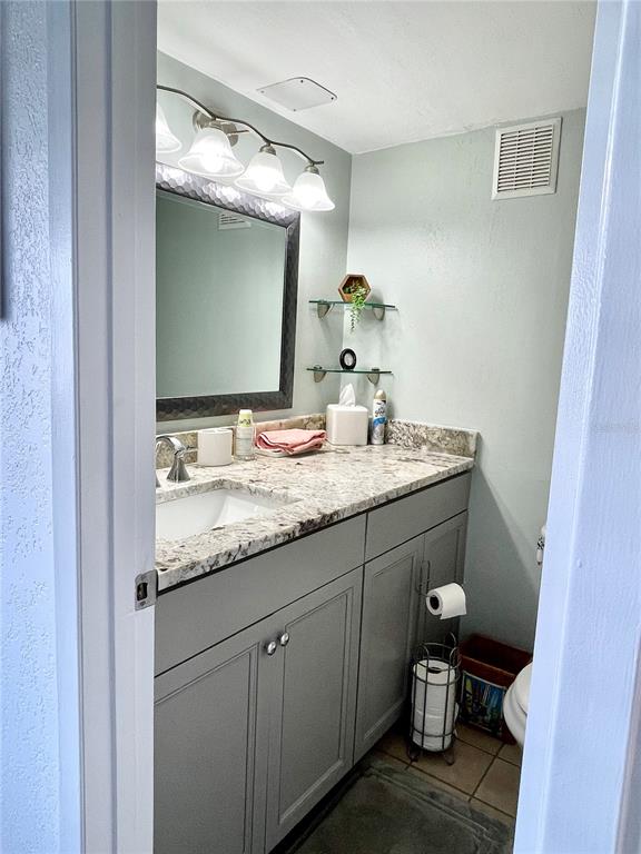 165 Medallion Boulevard, Unit H Madeira Beach, FL 33708 - Photo 17 of 20 a bathroom with a granite countertop sink toilet and mirror