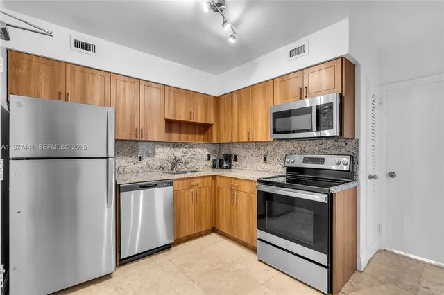 a kitchen with stainless steel appliances granite countertop a refrigerator stove a sink dishwasher and microwave