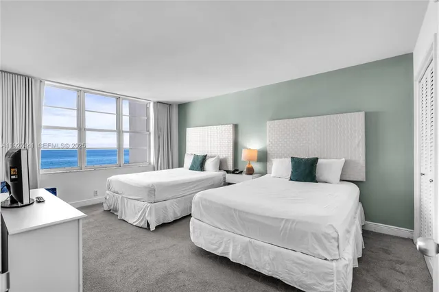 a bedroom with two beds and large window