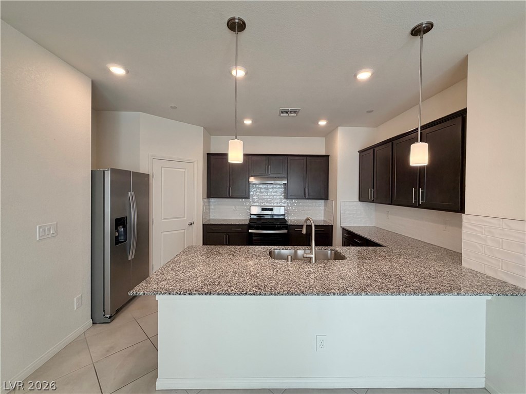 3624 Bitonto Lane Henderson, NV 89044 - Photo 4 of 28 This modern kitchen features a large island with granite counters, stainless steel appliances, and sleek cabinetry.