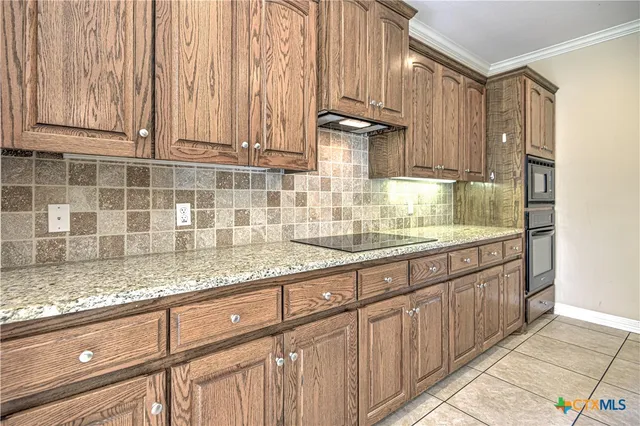 a kitchen with kitchen island granite countertop a sink stove and cabinets