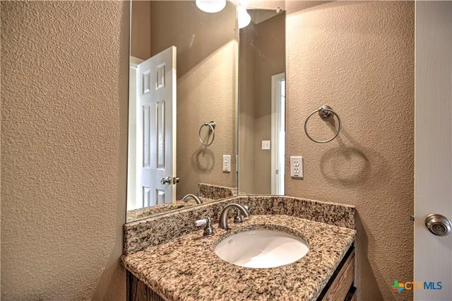 a bathroom with a granite countertop toilet a sink and a mirror