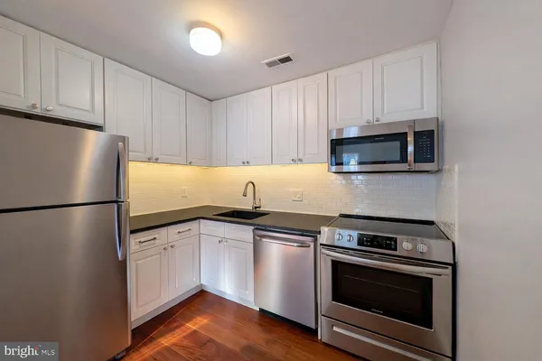 a kitchen with white cabinets and stainless steel appliances
