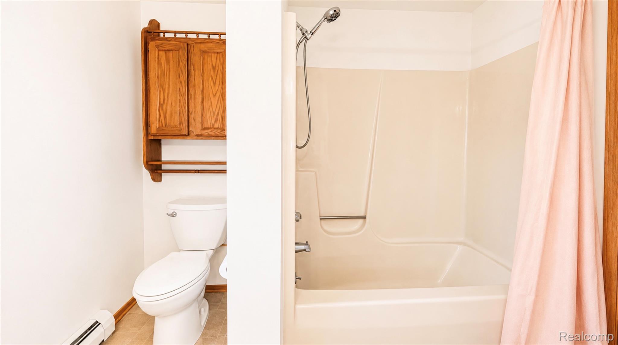 2232 London Bridge Drive, Unit 42 Rochester, MI 48307 - Photo 15 of 20 Bathroom featuring a shower-tub combination, a white toilet, wood-finish wall cabinetry, and baseboard heating