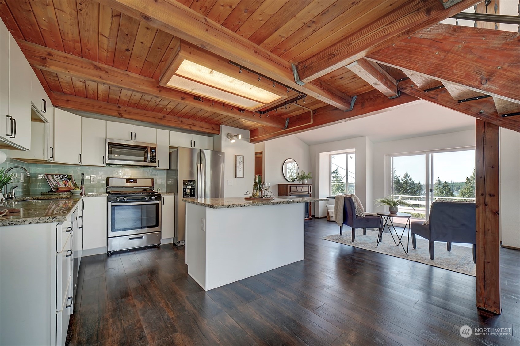 220 East Olympic Drive Grapeview, WA 98546 - Photo 6 of 40 a kitchen with stainless steel appliances granite countertop a stove a refrigerator a kitchen island a dining table and chairs with wooden floor