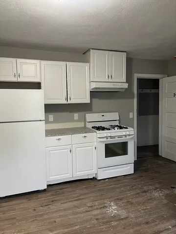 a kitchen with granite countertop white cabinets and white appliances