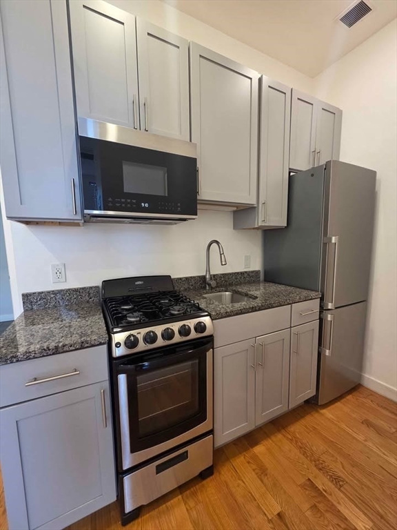 64 Market Street, Unit 408 Lynn, MA 01901 - Photo 3 of 9 a kitchen with stainless steel appliances white cabinets and a stove top oven