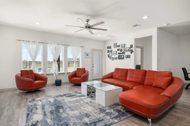 a living room with furniture kitchen view and a wooden floor
