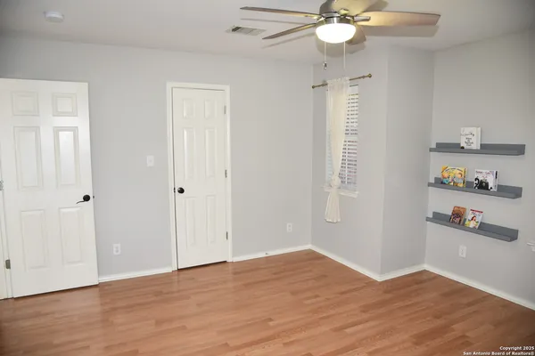 an empty room with wooden floor and ceiling fan