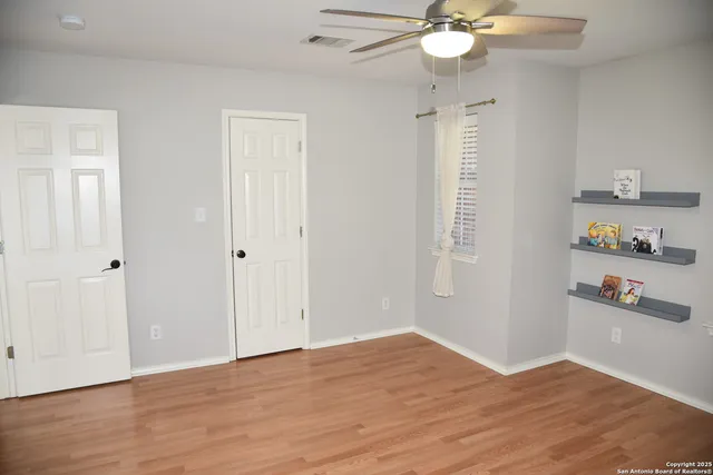 an empty room with wooden floor and ceiling fan
