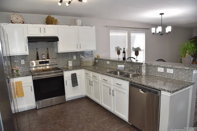 a kitchen with granite countertop stainless steel appliances a sink stove and cabinets