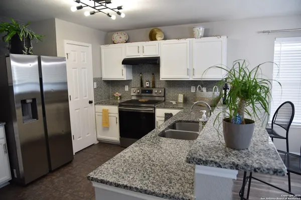 a kitchen with stainless steel appliances kitchen island granite countertop a refrigerator a stove and a sink