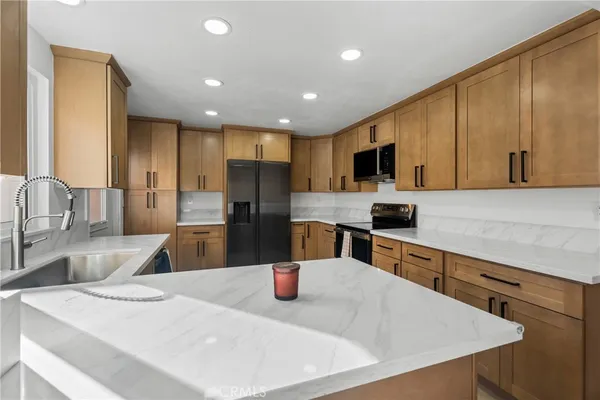 a kitchen with stainless steel appliances granite countertop a sink a stove and a refrigerator with wooden floor