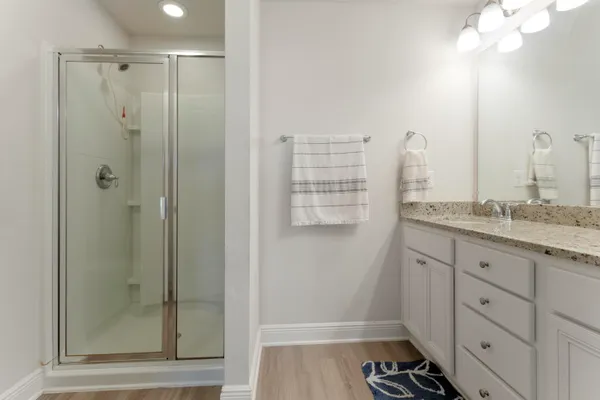 a bathroom with a granite countertop sink a mirror and a shower