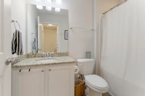 a bathroom with a granite countertop toilet sink and mirror