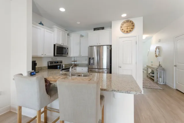 a kitchen with stainless steel appliances granite countertop a refrigerator a stove top oven a sink dishwasher and white cabinets with wooden floor