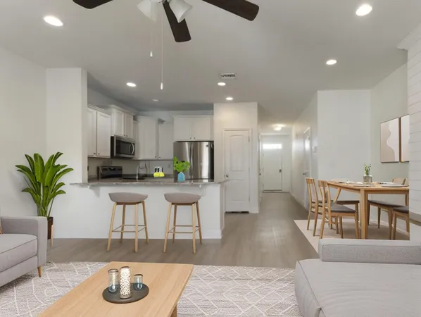 a kitchen with stainless steel appliances kitchen island granite countertop a refrigerator a stove a sink a dining table and chairs with wooden floor