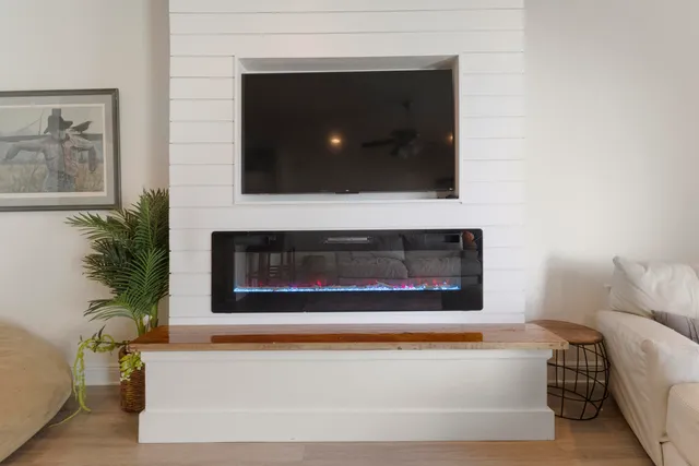 a living room with a fireplace and potted plant