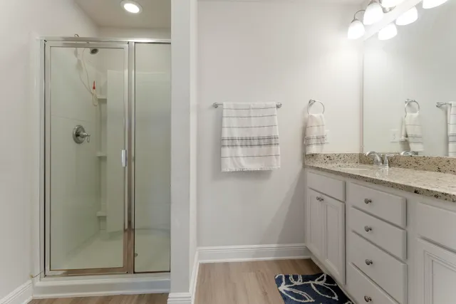 a bathroom with a granite countertop sink a mirror and a shower