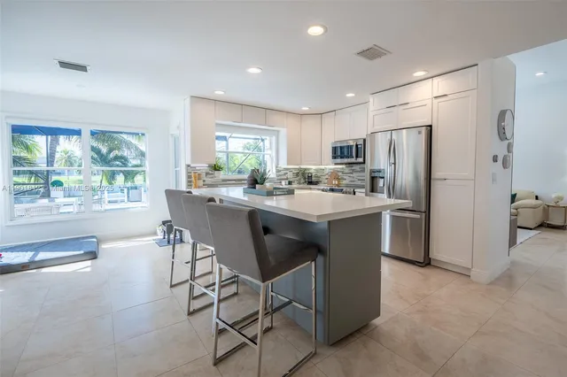 a kitchen with stainless steel appliances a dining table chairs refrigerator and sink