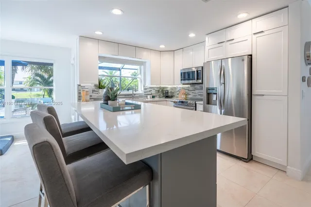 a kitchen with stainless steel appliances granite countertop a refrigerator a stove a dining table and chairs with wooden floor