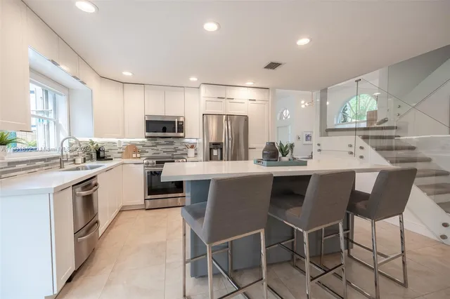 a kitchen with kitchen island granite countertop a sink counter and chairs