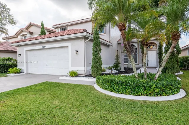 a view of a house with a small yard plants and palm trees
