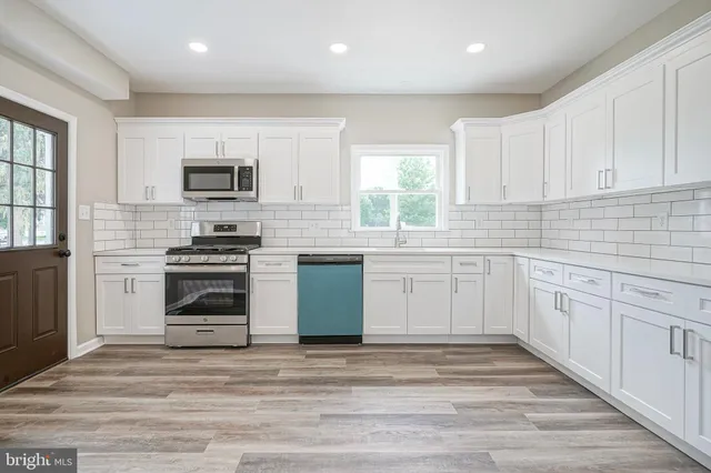a kitchen with white cabinets and stainless steel appliances