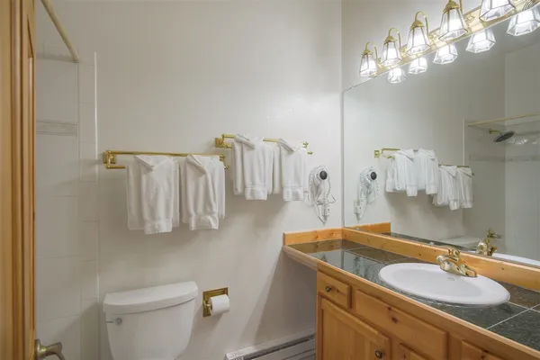 a bathroom with a granite countertop sink a toilet and a mirror