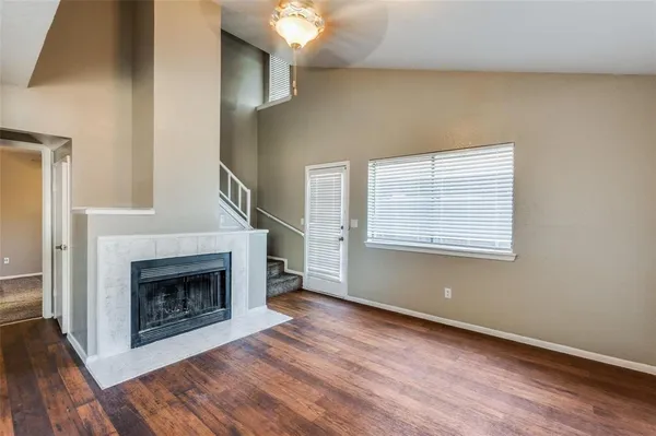 a view of an empty room with wooden floor fireplace and a window
