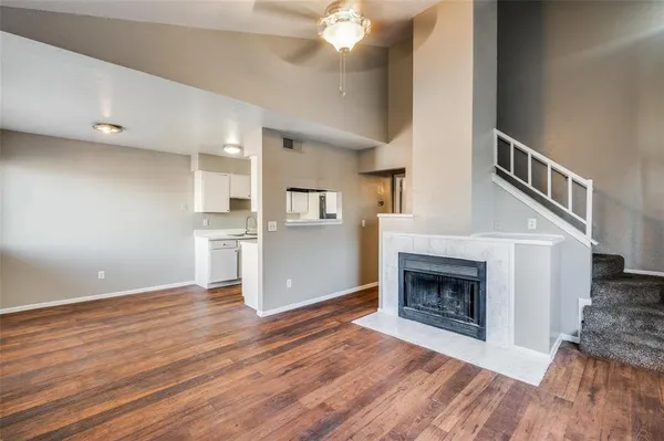 a view of kitchen and empty room with wooden floor