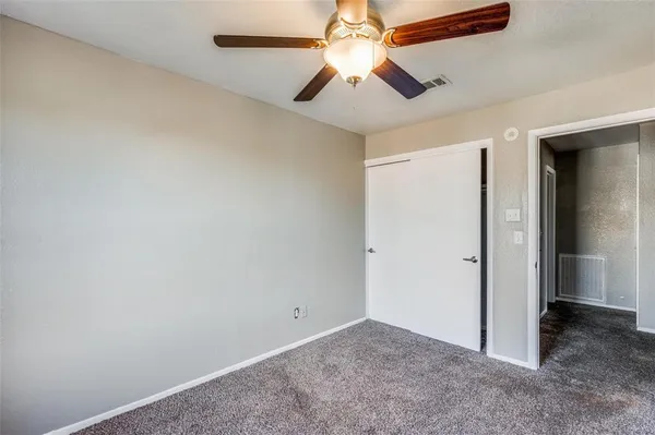 an empty room with a chandelier fan and closet