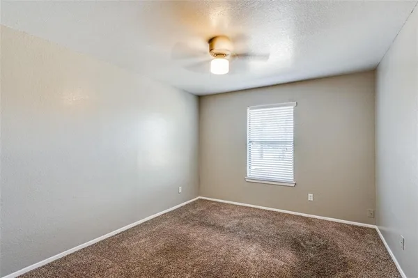 an empty room with a window and a ceiling fan